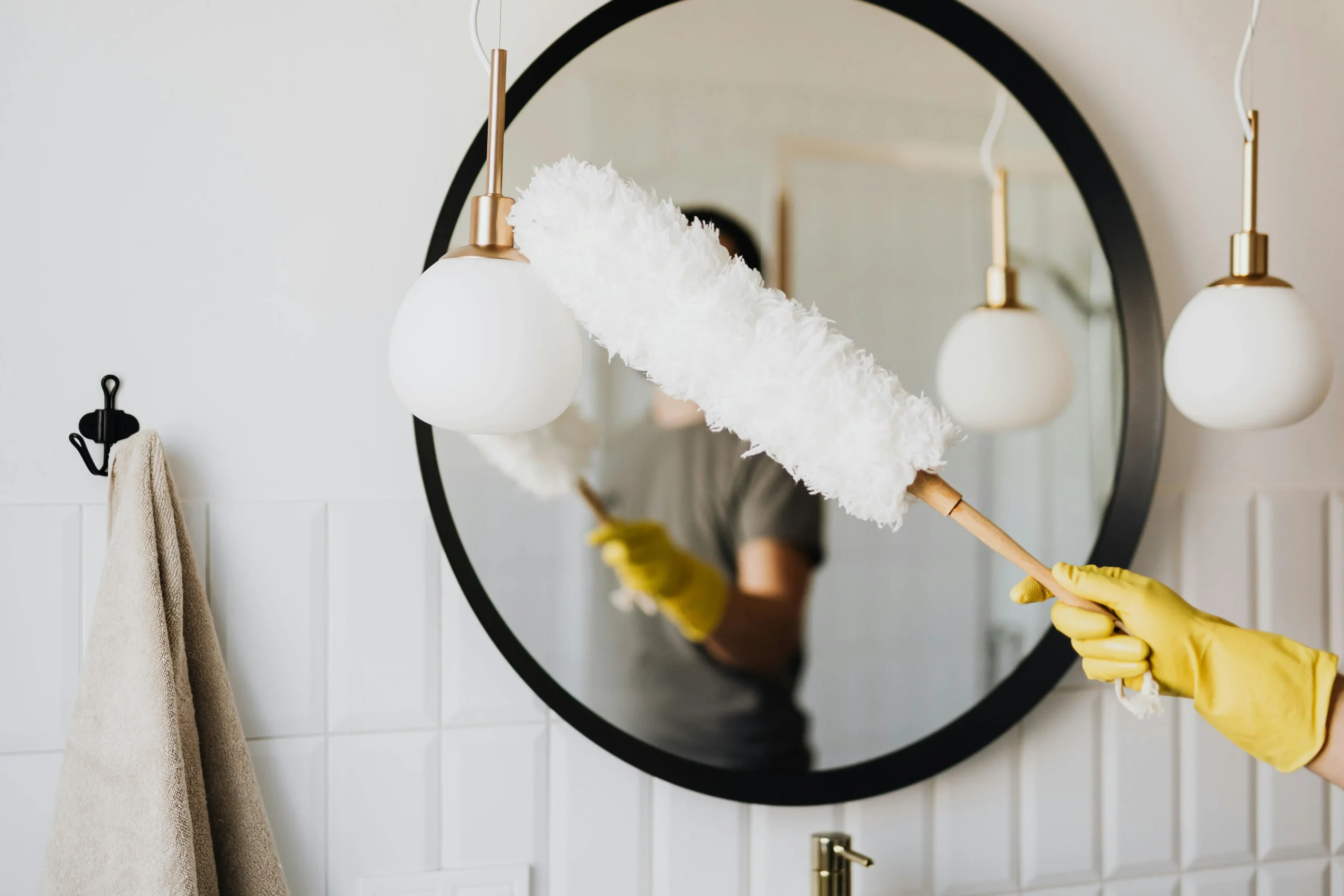 A professional cleaner dusting a mirror in a bedroom.