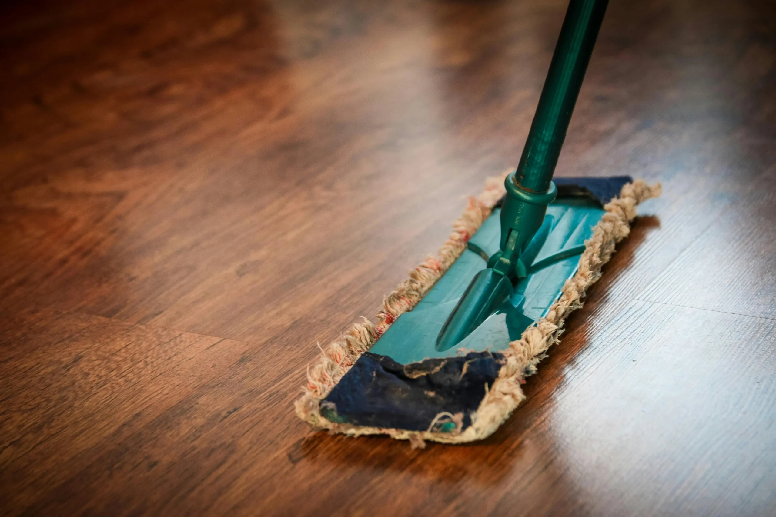 A mop being pushed across a hard surface floor.